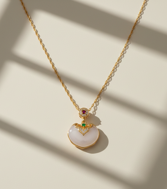 Gold necklace with a white pendant on a beige background