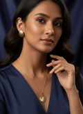 Woman wearing a gold necklace and earrings against a dark blue background