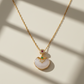 Gold necklace with a white pendant on a beige background